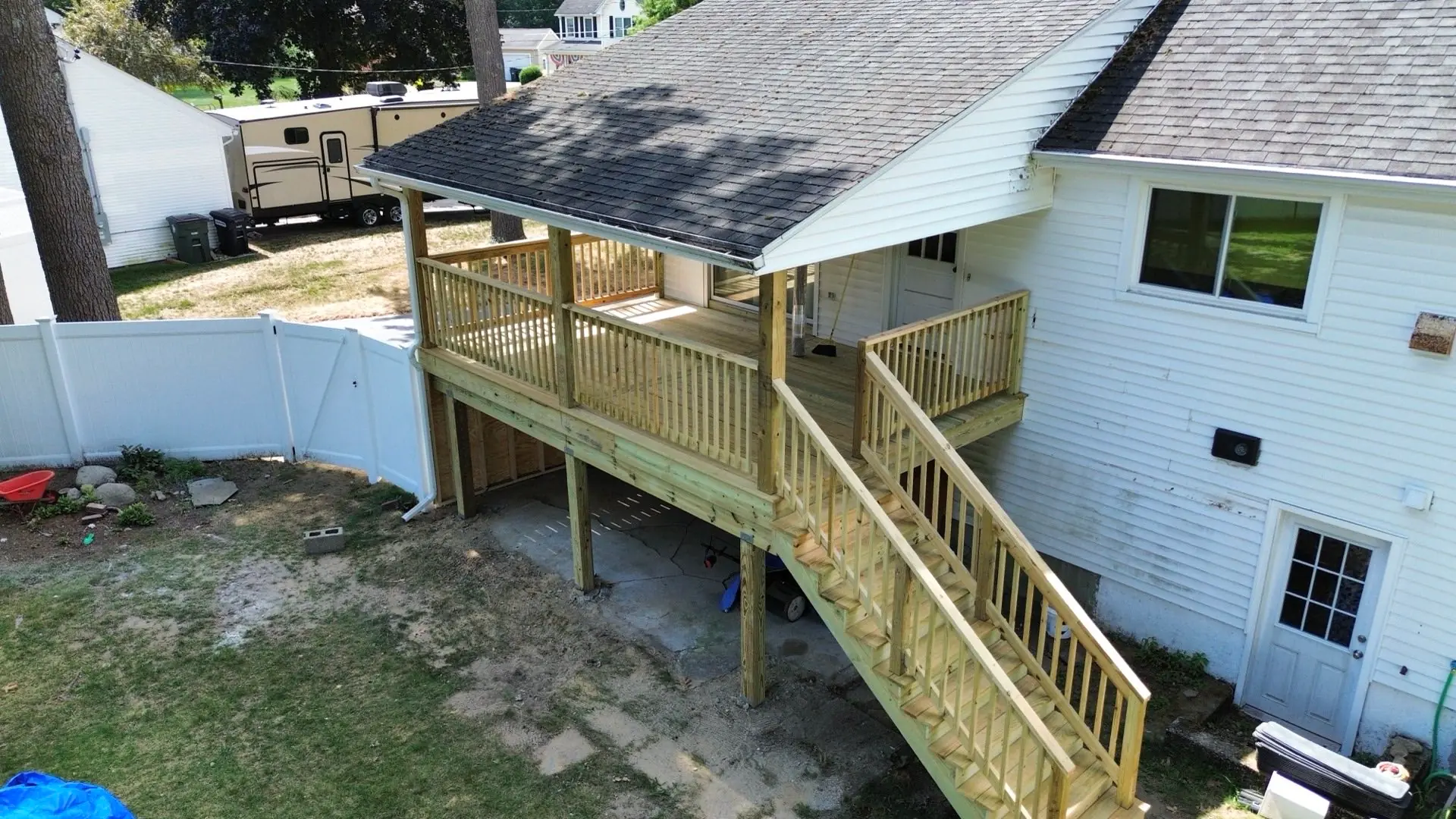Elevated covered porch with a shingled roof tied into the house, pressure-treated railings and a stair run down to grade