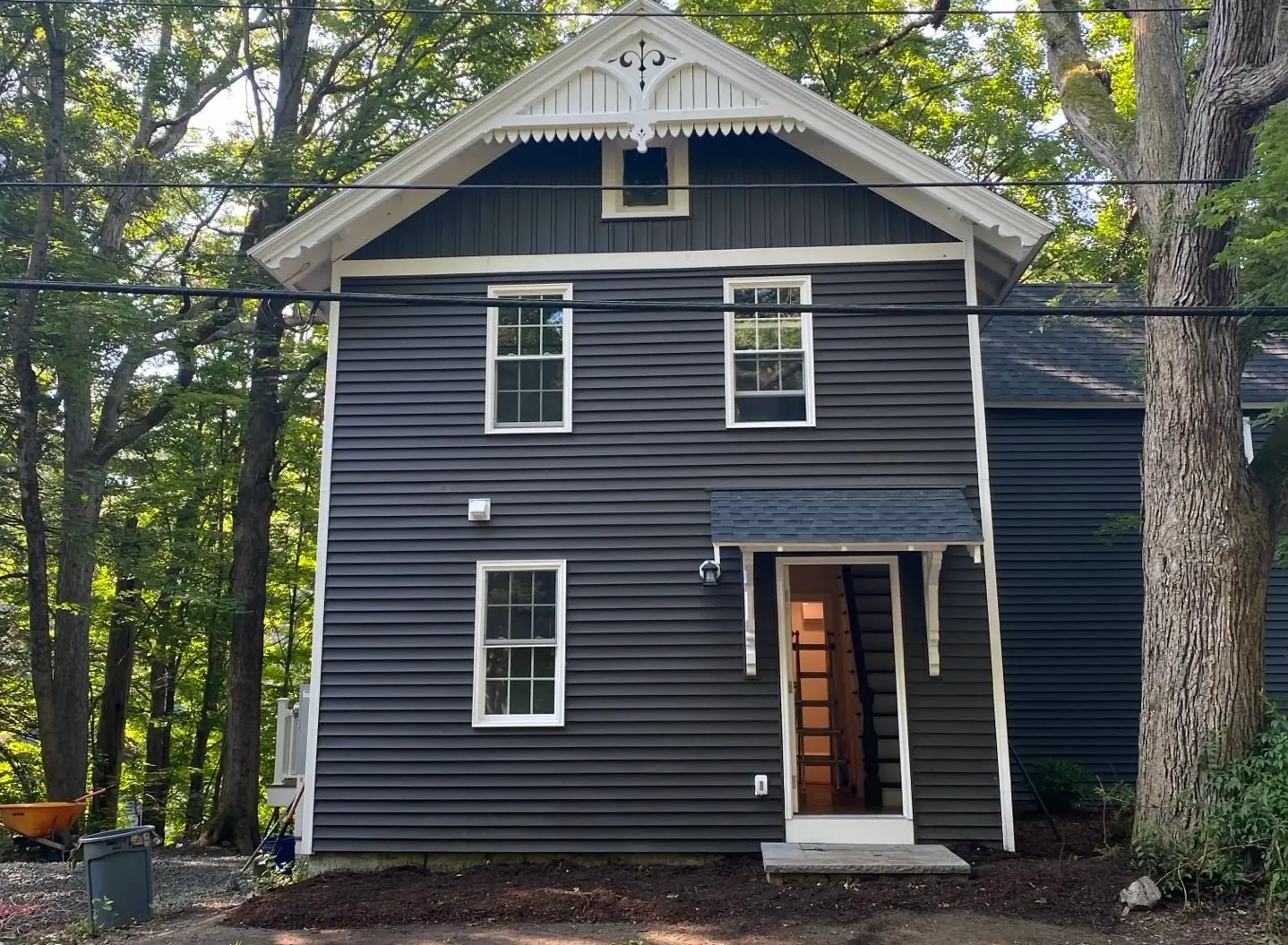 Full house re-side in dark gray horizontal clapboard with white trim, a board-and-batten gable, and decorative gable scrollwork